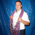 Man in white shirt holding purple cables in front of a blue background