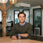 smiling Myo founder sitting at a wooden table in a modern coworking space