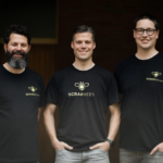 Three men wearing ScrapBees t-shirts standing side by side and smiling.