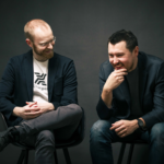 Two ChargeX founders smiling in front of a dark backdrop