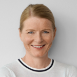 Blonde woman with short hair in a white blouse smiling