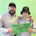 Circu Li-ion team in caps and gray hoodies holding a green sign.