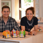 Two co-founders of Sira smiling at a table with colorful wooden toy cars