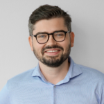 Man with glasses and beard wearing a light blue shirt