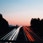Long exposure photo of highway traffic lights at sunset.