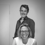 Two smiling business professionals in an office environment, black and white image.